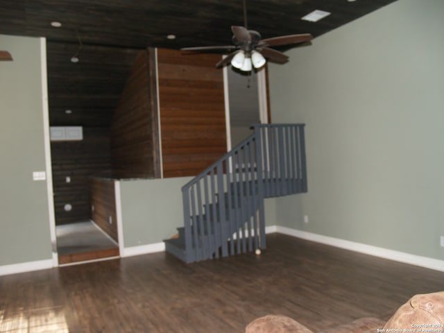 staircase featuring ceiling fan, hardwood / wood-style flooring, wooden walls, and vaulted ceiling