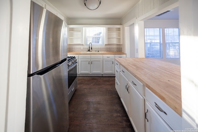 kitchen with sink, white cabinets, butcher block counters, appliances with stainless steel finishes, and dark hardwood / wood-style flooring