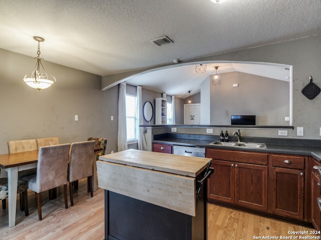 kitchen featuring lofted ceiling, sink, decorative light fixtures, a center island, and light hardwood / wood-style floors