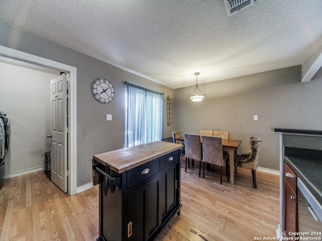 kitchen with pendant lighting, dishwasher, light hardwood / wood-style floors, a kitchen island, and wooden counters