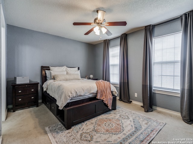 carpeted bedroom featuring a textured ceiling and ceiling fan