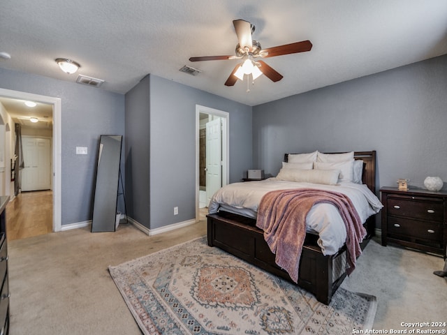 bedroom with light carpet, ceiling fan, ensuite bathroom, and a textured ceiling