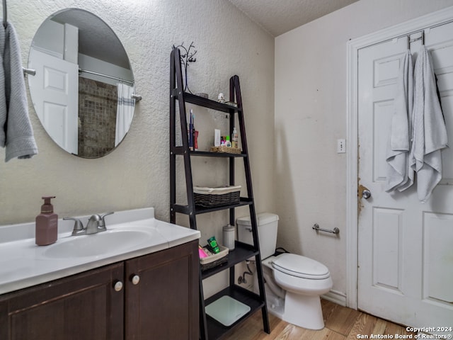 bathroom with vanity, curtained shower, a textured ceiling, hardwood / wood-style flooring, and toilet