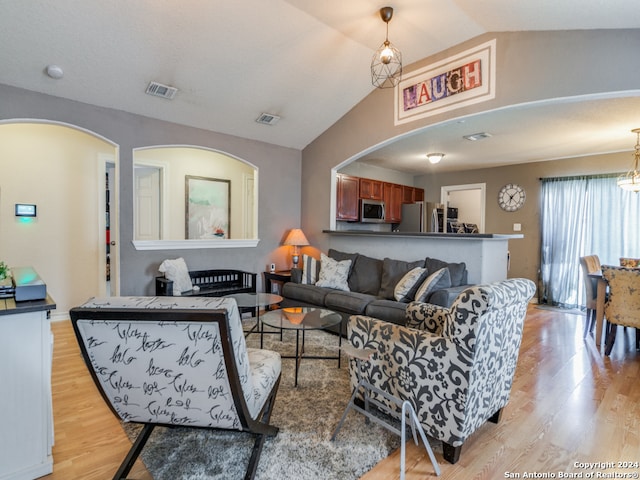 living room featuring an inviting chandelier, light wood-type flooring, and vaulted ceiling