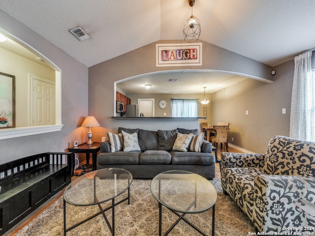 living room featuring a textured ceiling, lofted ceiling, a chandelier, and hardwood / wood-style floors