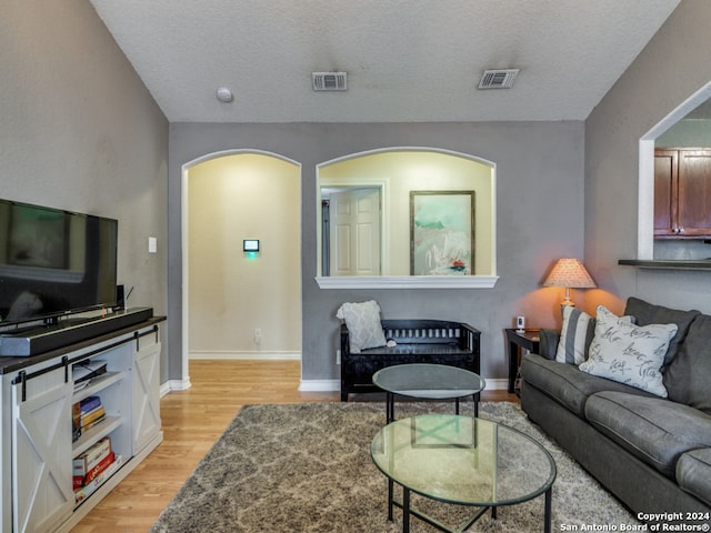 living room featuring light wood-type flooring and a textured ceiling