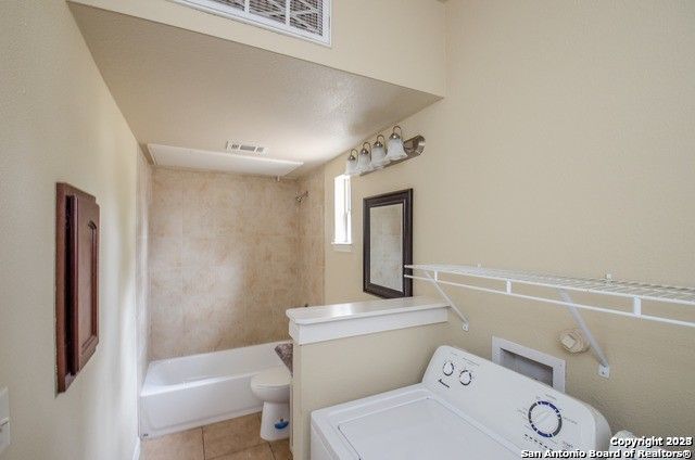 bathroom with washer / clothes dryer, toilet,  shower combination, and tile patterned floors