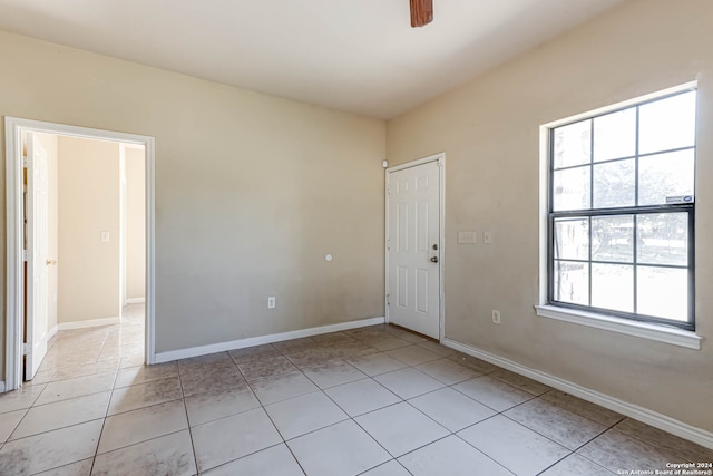 empty room with ceiling fan and light tile patterned floors