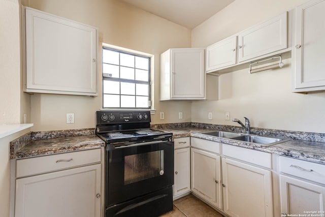 kitchen featuring black electric range, sink, light tile patterned floors, and white cabinets