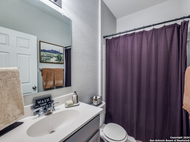 bathroom with curtained shower, vanity, and toilet