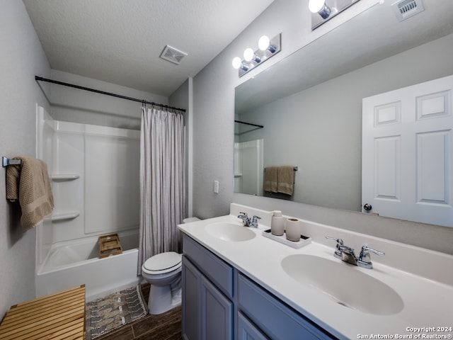 full bathroom featuring a textured ceiling, vanity, shower / bath combo with shower curtain, and toilet