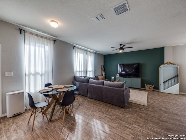 living room with hardwood / wood-style flooring, a textured ceiling, and ceiling fan