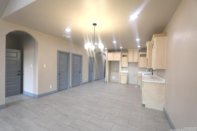 kitchen with pendant lighting, a chandelier, light stone countertops, and sink