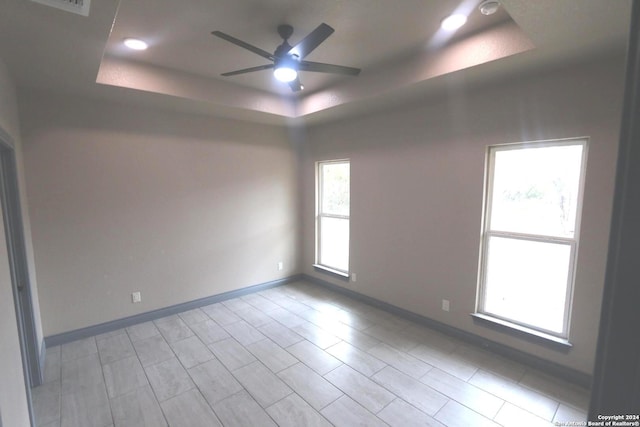 empty room with a tray ceiling and ceiling fan