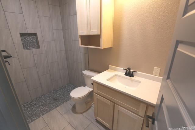 bathroom with vanity, tile patterned floors, toilet, and tiled shower