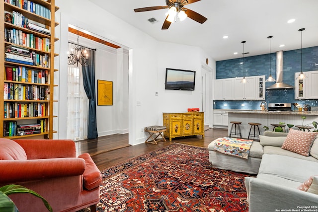 living room with ceiling fan with notable chandelier, sink, and dark wood-type flooring