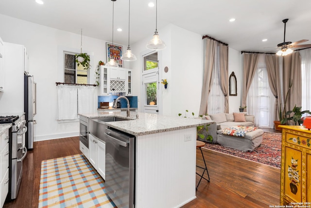 kitchen with an island with sink, stainless steel appliances, white cabinets, and a healthy amount of sunlight