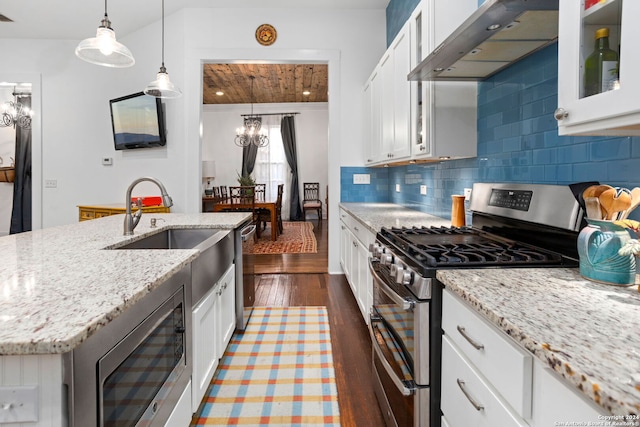 kitchen with a chandelier, dark hardwood / wood-style floors, range hood, white cabinetry, and appliances with stainless steel finishes