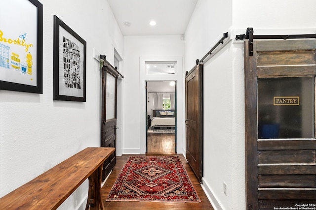 corridor with a barn door and dark hardwood / wood-style flooring