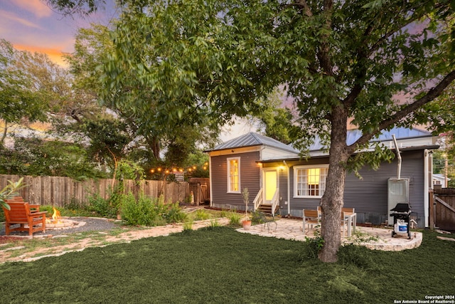 back house at dusk featuring a yard and a patio area