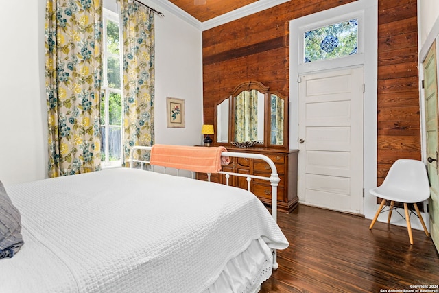 bedroom with crown molding, wood walls, and dark hardwood / wood-style floors