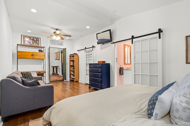 bedroom featuring a barn door, ceiling fan, and dark wood-type flooring