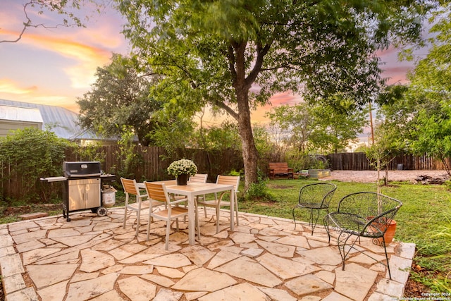 patio terrace at dusk with a yard and a grill