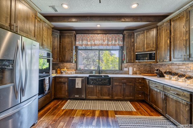 kitchen with decorative backsplash, appliances with stainless steel finishes, plenty of natural light, and dark hardwood / wood-style flooring