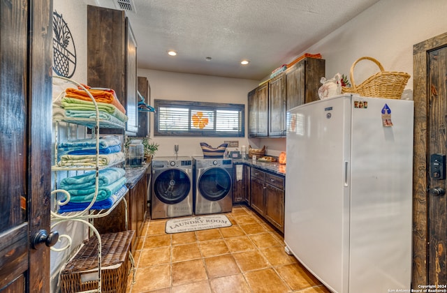 laundry area featuring cabinets, a textured ceiling, light tile patterned floors, and washer and dryer