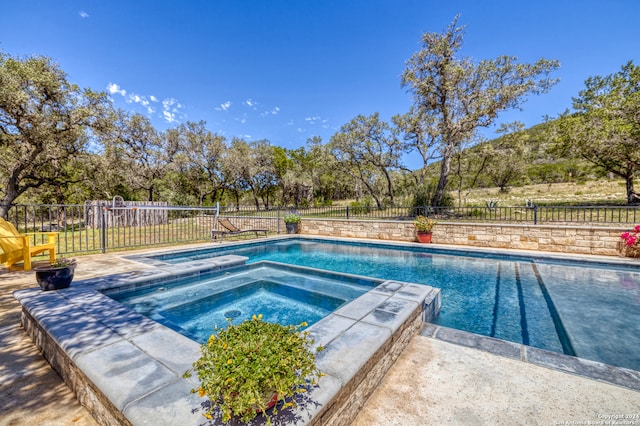 view of swimming pool with an in ground hot tub