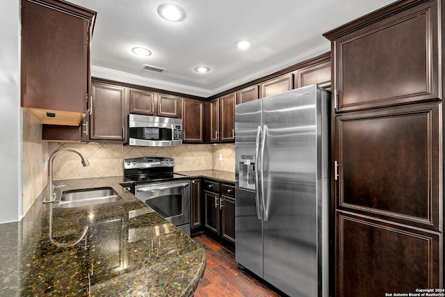 kitchen with appliances with stainless steel finishes, dark stone countertops, dark hardwood / wood-style flooring, dark brown cabinets, and sink