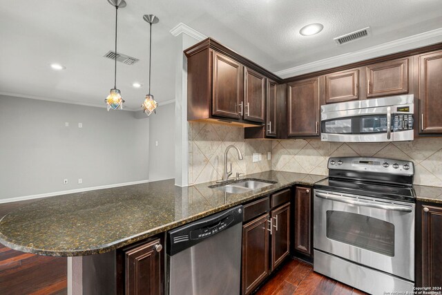 kitchen featuring dark hardwood / wood-style floors, sink, kitchen peninsula, stainless steel appliances, and decorative light fixtures