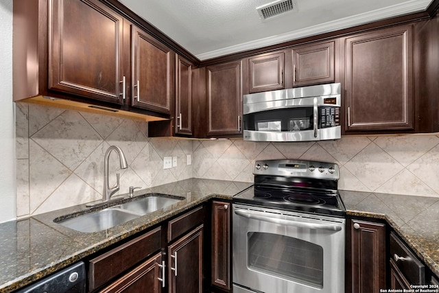 kitchen featuring sink, dark brown cabinets, stainless steel appliances, dark stone counters, and decorative backsplash