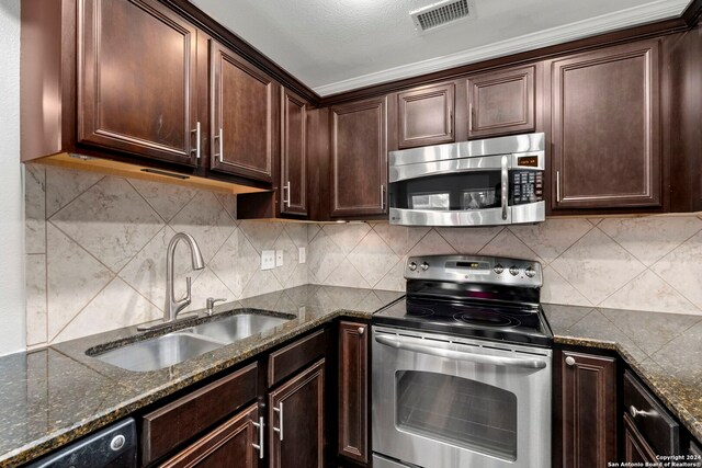 kitchen with dark stone counters, appliances with stainless steel finishes, dark brown cabinets, a sink, and visible vents