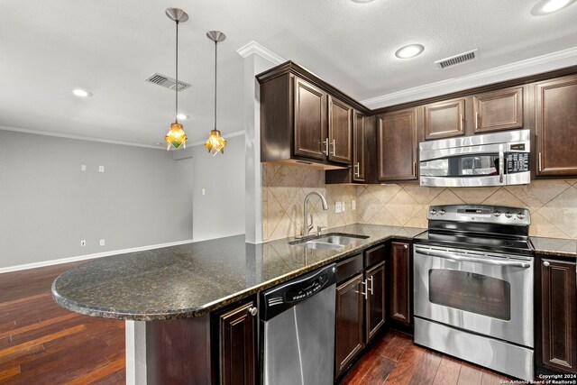 kitchen featuring dark brown cabinetry, stainless steel appliances, ornamental molding, and a sink