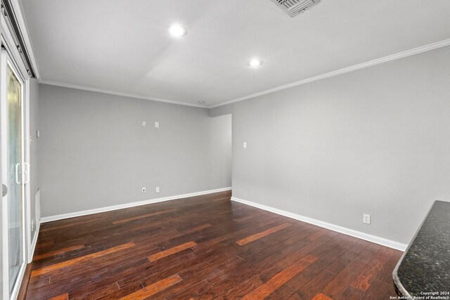 empty room featuring visible vents, baseboards, dark wood-style flooring, recessed lighting, and ornamental molding