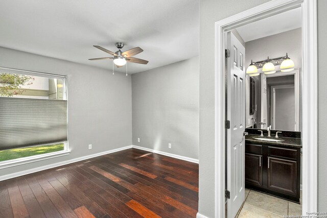 unfurnished bedroom featuring ceiling fan, hardwood / wood-style floors, baseboards, and a sink