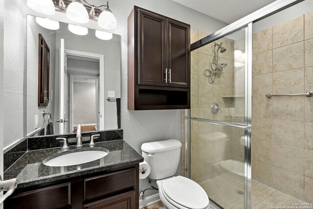 bathroom featuring toilet, a shower stall, and vanity