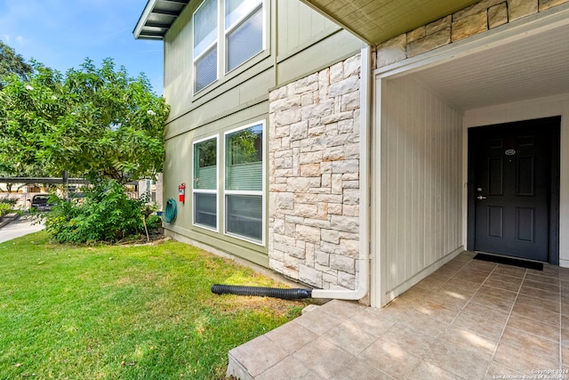 doorway to property featuring a yard and stone siding
