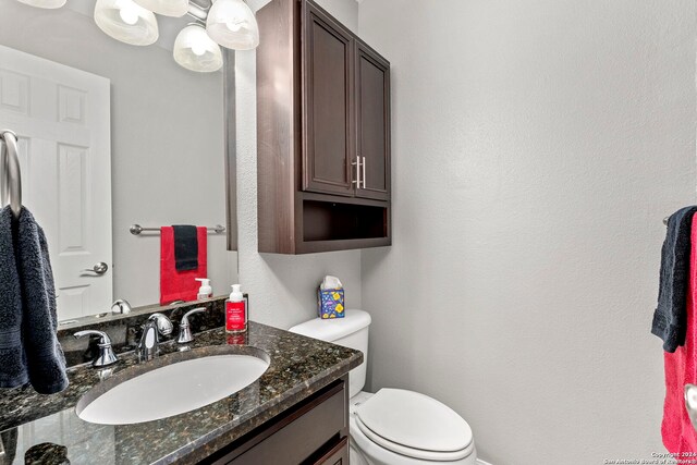 bathroom with vanity, toilet, and a textured wall
