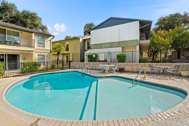 community pool with fence and a patio area