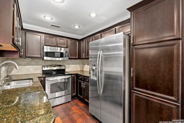 kitchen featuring dark brown cabinetry, sink, stainless steel appliances, dark hardwood / wood-style floors, and dark stone countertops