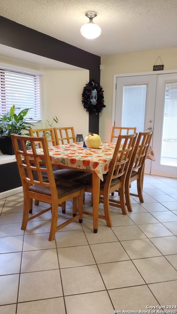 dining space featuring a textured ceiling, light tile patterned floors, and a wealth of natural light