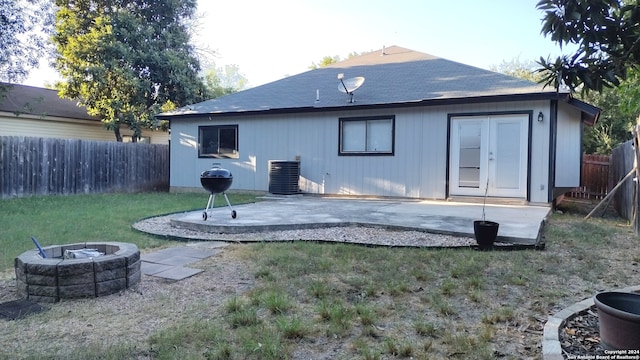 back of house featuring cooling unit, a fire pit, a yard, and a patio