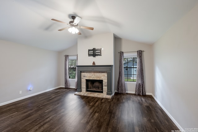 unfurnished living room featuring a brick fireplace, dark wood-type flooring, ceiling fan, and a healthy amount of sunlight