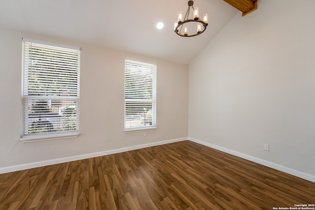 empty room featuring vaulted ceiling, a chandelier, and dark wood-type flooring