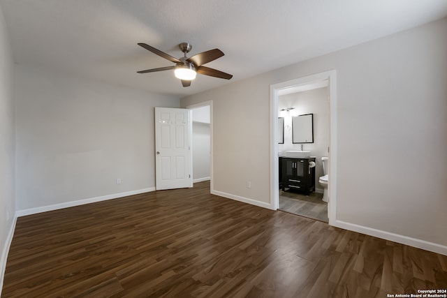 unfurnished bedroom featuring ensuite bath, ceiling fan, and dark wood-type flooring