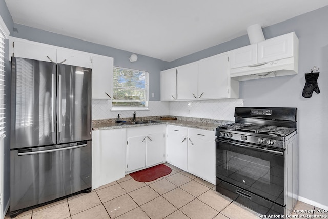 kitchen featuring white cabinets, light tile patterned flooring, stainless steel fridge, tasteful backsplash, and black gas range oven