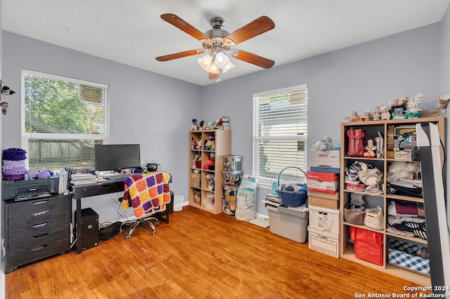 home office with light hardwood / wood-style flooring and ceiling fan