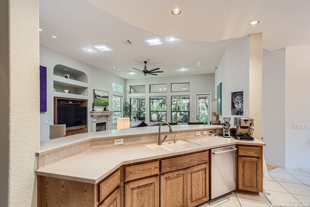 kitchen with dishwasher, sink, kitchen peninsula, light tile patterned floors, and ceiling fan